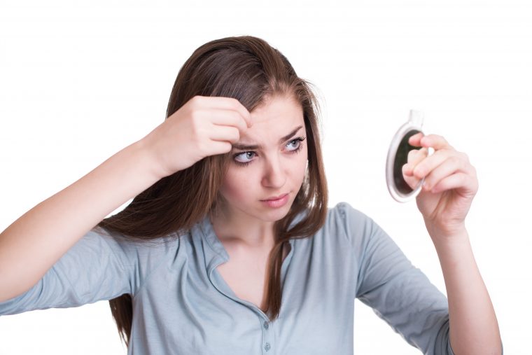 Woman looking at the first grey hair on her scalp